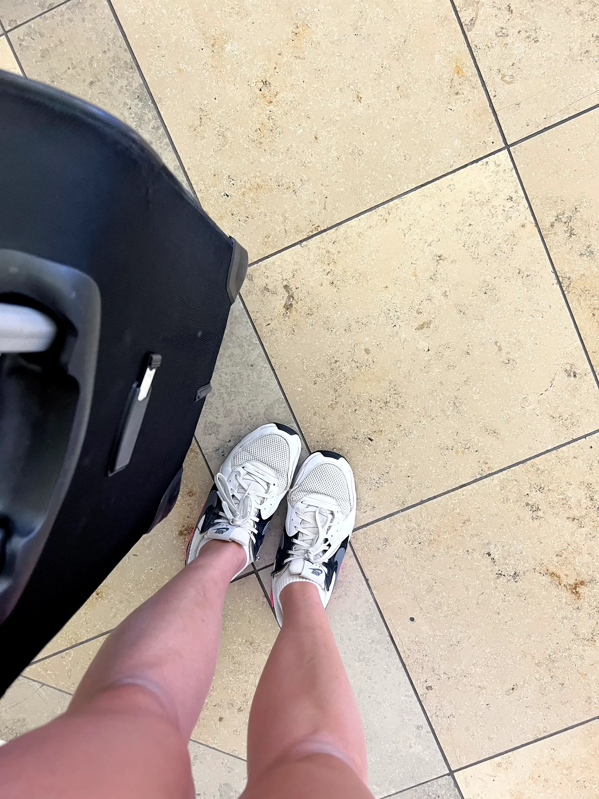 looking down at legs, shoes and suitcase